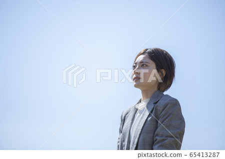 站立反對藍天的衣服的年輕女商人 65413287