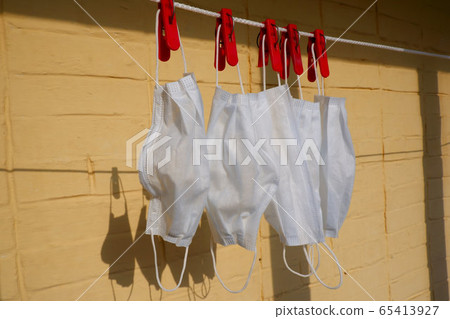 Washed white medical masks hanging on clothesline 65413927