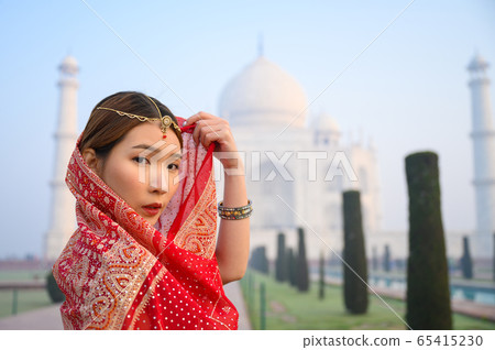 Asian woman wearing red saree Indian traditional dress against Taj Mahal Asian woman wearing red saree Indian traditional dress against Taj Mahal 65415230