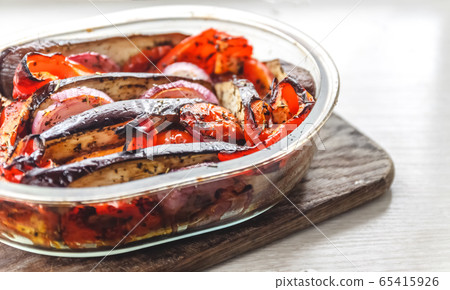 Baked vegetables tomatoes, eggplants, blue onions, zucchini, zucchini in glass form on a bright 65415926