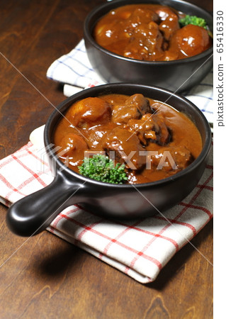 Beef stew on two black one-handed plates, brown wood back Beef stew on two black one-handed plates, brown wood back 65416330