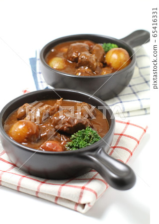 Beef stew on two black one-handed plates, white background Beef stew on two black one-handed plates, white background 65416331