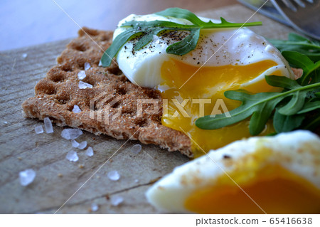 Poached egg on a whole grain bread with arugula Poached egg on a whole grain bread with arugula 65416638