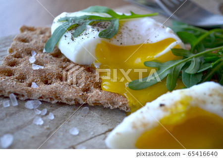 Poached egg on a whole grain bread with arugula Poached egg on a whole grain bread with arugula 65416640