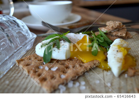 Poached egg on a whole grain bread with arugula Poached egg on a whole grain bread with arugula 65416643
