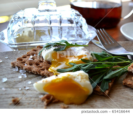 Poached egg on a whole grain bread with arugula Poached egg on a whole grain bread with arugula 65416644