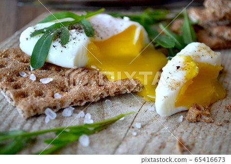 Poached egg on a whole grain bread with arugula on 65416673