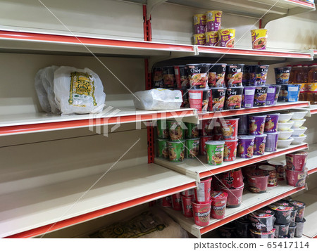 The shelves at the supermarket became empty due to panic buying. Customers buy necessities in excessive quantities resulting in stock depletion. The shelves at the supermarket became empty due to panic buying. Customers buy necessities in excessive quantities resulting in stock depletion. 65417114