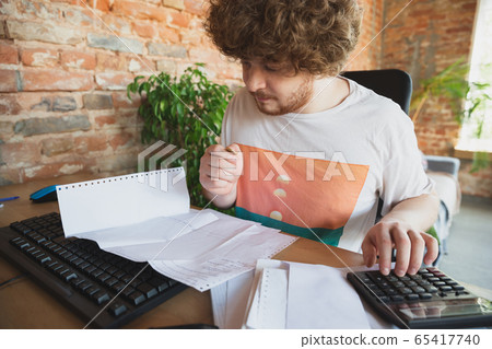 Caucasian upset and despair man doing financial and economical reports with income going down during coronavirus quarantine, problems Caucasian upset and despair man doing financial and economical reports with income going down during coronavirus quarantine, problems 65417740