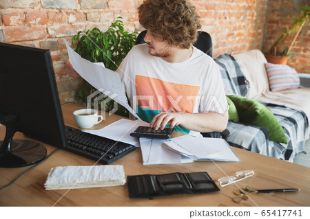 Caucasian upset and despair man doing financial and economical reports with income going down during coronavirus quarantine, problems Caucasian upset and despair man doing financial and economical reports with income going down during coronavirus quarantine, problems 65417741