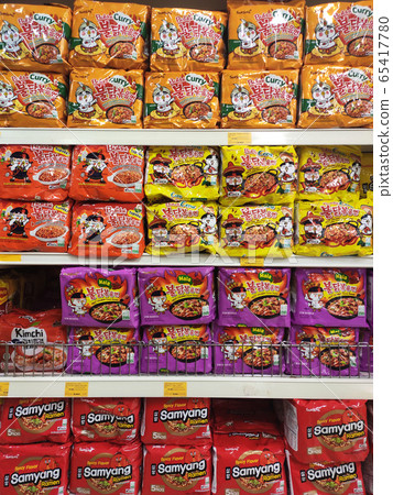KUALA LUMPUR, MALAYSIA -FEBRUARY 2, 2020: Various brands of instant noodles in a commercial packages stacked for sale on the display shelves in supermarkets. KUALA LUMPUR, MALAYSIA -FEBRUARY 2, 2020: Various brands of instant noodles in a commercial packages stacked for sale on the display shelves in supermarkets. 65417780