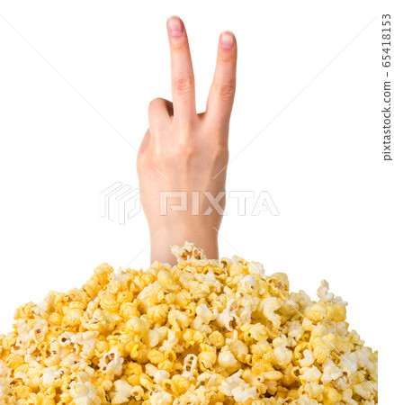 Female hand sticks out of a pile of popcorn isolated on white background Female hand sticks out of a pile of popcorn isolated on white background 65418153