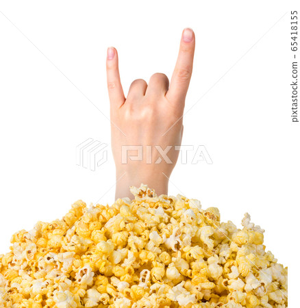 Female hand sticks out of a pile of popcorn isolated on white background 65418155