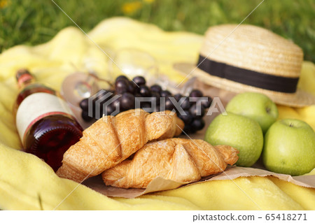 Picnic on the grass with croissant, pink wine, straw hat, grape on yellow plaid Picnic on the grass with croissant, pink wine, straw hat, grape on yellow plaid 65418271