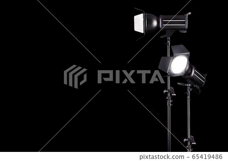 Photography studio flash on a lighting stand isolated on black background. Photography studio flash on a lighting stand isolated on black background. 65419486