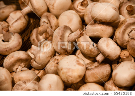 White champignons lie on a store shelf 65420198
