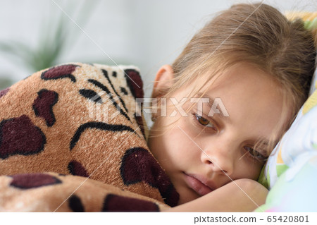 Girl slowly wakes up, lying in bed and covered 65420801