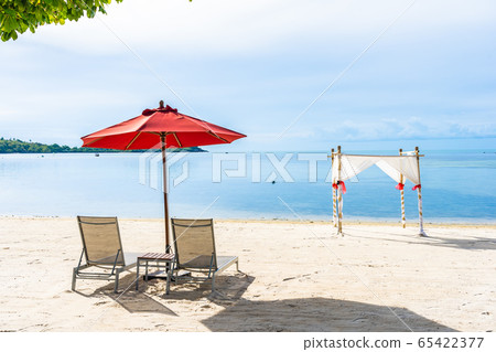 Beautiful outdoor tropical beach sea ocean with umbrella chair and lounge deck around there on white cloud blue sky 65422377