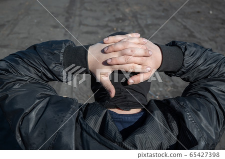the hands of the detained bandit are closed behind the head the hands of the detained bandit are closed behind the head 65427398