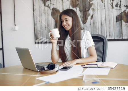 Young student sitting at the table and use the laptop Young student sitting at the table and use the laptop 65427519