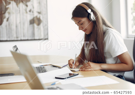 Young student sitting at the table and use the laptop Young student sitting at the table and use the laptop 65427593