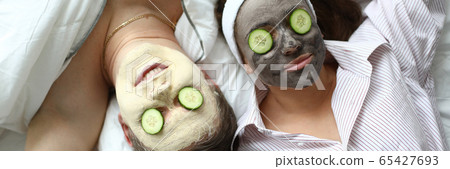 Couple lying on bed with cosmetic mask on face 65427693
