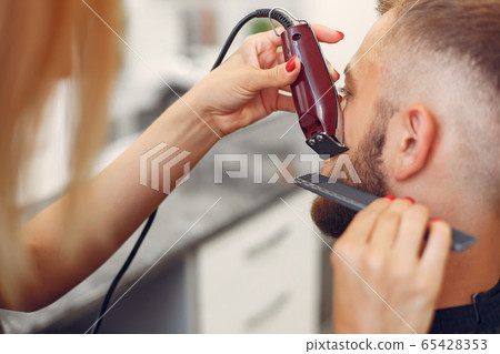 Woma shaving man's beard in a barbershop 65428353