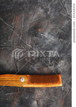 Folding wooden comb on a black background. 65428354
