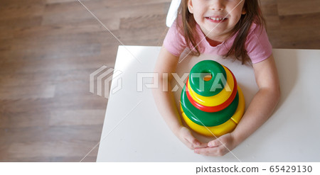 the child collects a pyramid. Details of the toy in the hands. Concept of development of fine motor skills, educational games, childhood, IVF, children's day, kindergarten copy space 65429130