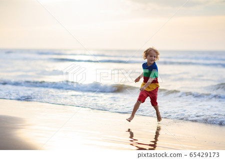 Child playing on ocean beach. Kid at sunset sea. 65429173