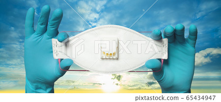 Hands wearing doctor gloves holding protective mask 65434947