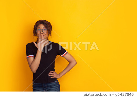 African-american beautiful young woman's portrait on yellow studio background, emotional and expressive. Copyspace for ad. African-american beautiful young woman's portrait on yellow studio background, emotional and expressive. Copyspace for ad. 65437846