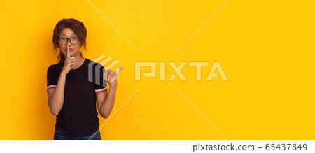 African-american beautiful young woman's portrait on yellow studio background, emotional and expressive. Flyer with copyspace for ad. African-american beautiful young woman's portrait on yellow studio background, emotional and expressive. Flyer with copyspace for ad. 65437849