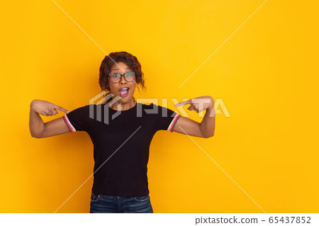 African-american beautiful young woman's portrait on yellow studio background, emotional and expressive. Copyspace for ad. African-american beautiful young woman's portrait on yellow studio background, emotional and expressive. Copyspace for ad. 65437852