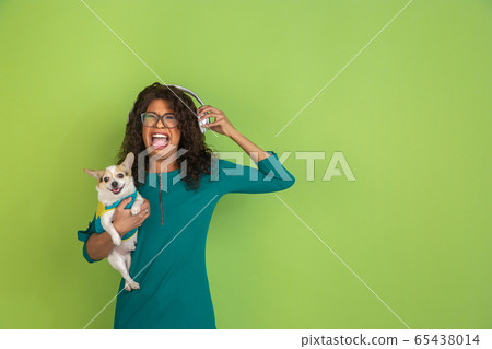 African-american beautiful young woman's portrait with little doggy on green studio background, emotional and expressive. Copyspace for ad. African-american beautiful young woman's portrait with little doggy on green studio background, emotional and expressive. Copyspace for ad. 65438014