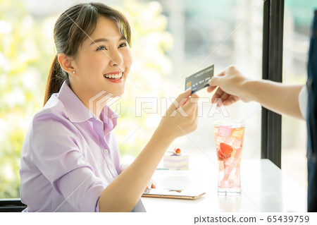 年輕漂亮的女人咖啡館付款信用卡業務員交出材料 年輕漂亮的女人咖啡館付款信用卡業務員交出材料 65439759