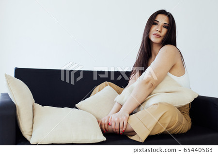 Beautiful fashionable eastern brunette woman on the black sofa Beautiful fashionable eastern brunette woman on the black sofa 65440583