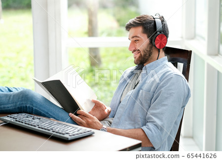Handsome business man with casual cloth is listening some music from computer 65441626