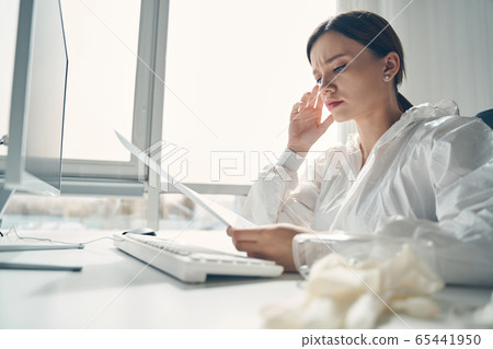 Beautiful young woman studying papers at work Beautiful young woman studying papers at work 65441950