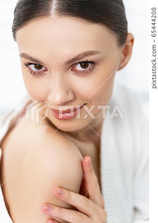 Pretty female in white bathrobe looking ahead 65444208