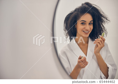 Woman with a lip balm posing for the camera 65444402