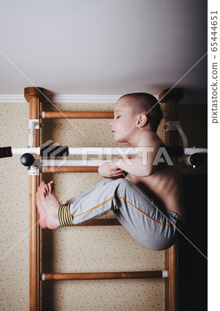 Home workout. The boy raises his legs in the hang 65444651