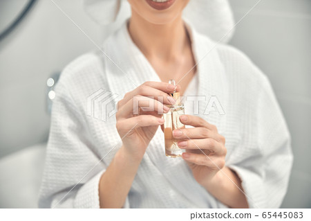 Caucasian woman posing for camera with face serum 65445083