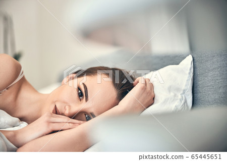 Happy Caucasian woman looking at camera in bedroom Happy Caucasian woman looking at camera in bedroom 65445651