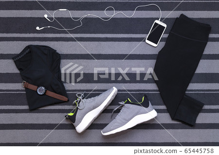 Top view of running shoes, womens clothes, pants tights, smartphone run application isolated on grey carpet. Top view of running shoes, womens clothes, pants tights, smartphone run application isolated on grey carpet. 65445758