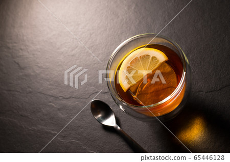 Top view image of a cup of tea with lemon on black granite background 65446128