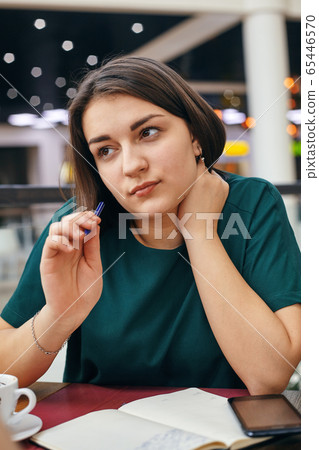 Young beautiful girl writes something in her notebook while sitting in the office 65446570