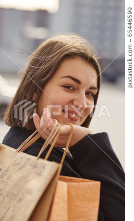 Smiling girl with shopping bags in a city 65446599