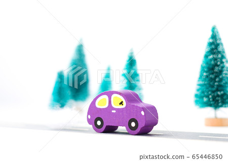 Wooden car on paper road against fir-trees on white background. Traffic on country road Wooden car on paper road against fir-trees on white background. Traffic on country road 65446850