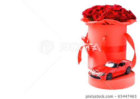 Red toy modern car against luxury red roses in paper hat box on white background. Romantic gift for woman Red toy modern car against luxury red roses in paper hat box on white background. Romantic gift for woman 65447463